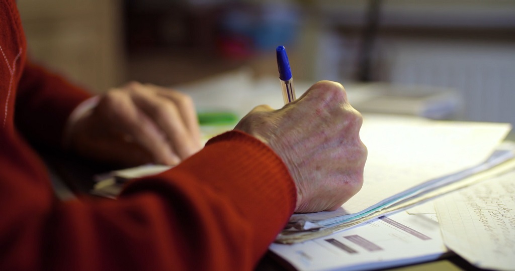 Starija osoba potpisuje dokument koji reguliše ugovor o doživotnom izdržavanju