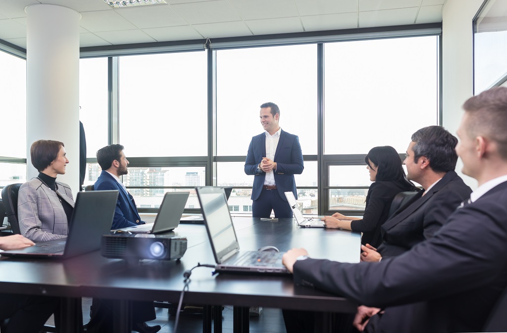 Poslovni tim na sastanku u kancelariji sa prezentacijom i laptopovima