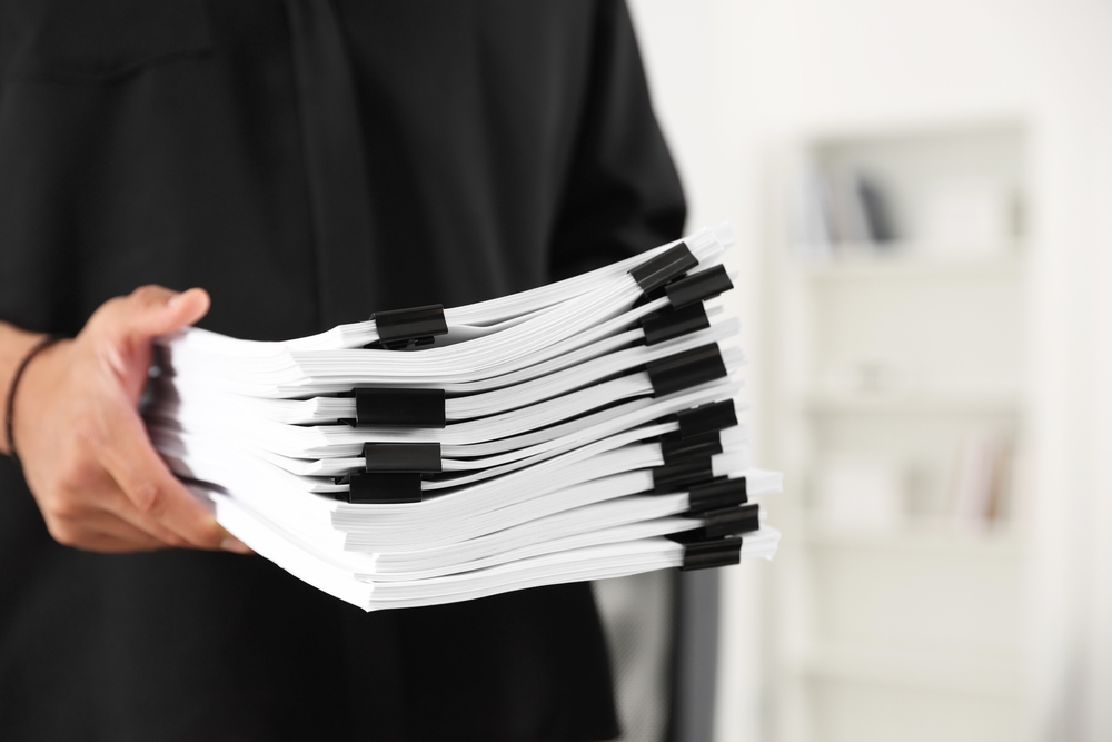 Osoba drži složene dokumente povezane klipsama spremne za arhiviranje