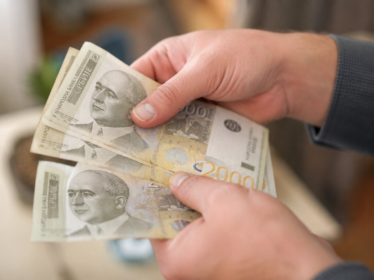 Građanin drži novčanice od 2.000 dinara tokom brojanja novca
